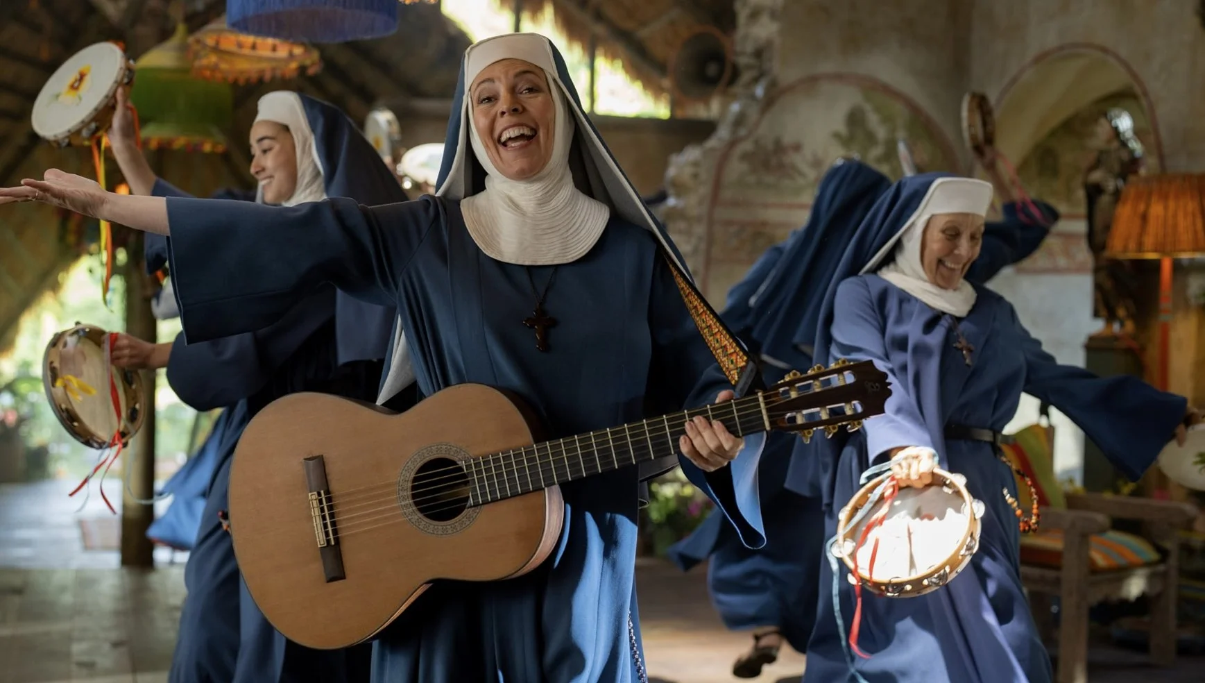 Olivia colman cantando con una sonrisa en la cara.